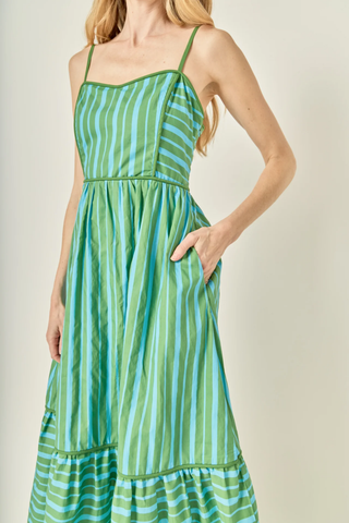 Green and blue striped dress worn by a person on a plain background