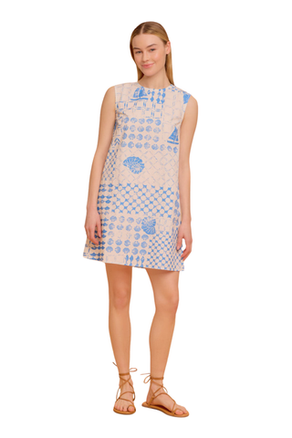 Model wearing the Olivia by Livro Wynn Dress in Sea Atlas featuring a sleeveless shift silhouette, blue coastal-inspired patchwork print with shell and sailboat motifs, mini length, and lace-up flat sandals
