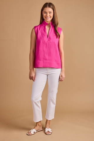 Model wearing the Double A Sandy Top in Fuchsia featuring a sleeveless silhouette, stand collar, split neckline, and relaxed fit paired with white denim