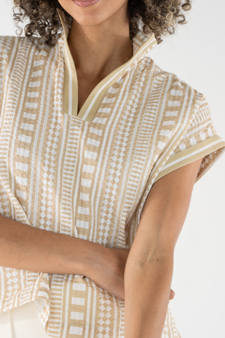 Woman wearing a patterned beige and white dress on a white background