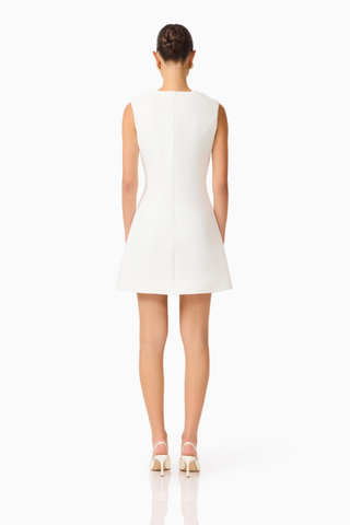 Model wearing the Elliatt Reina Mini Dress in White featuring a sleeveless silhouette, intricate 3D floral appliqué, and a structured A-line mini dress.