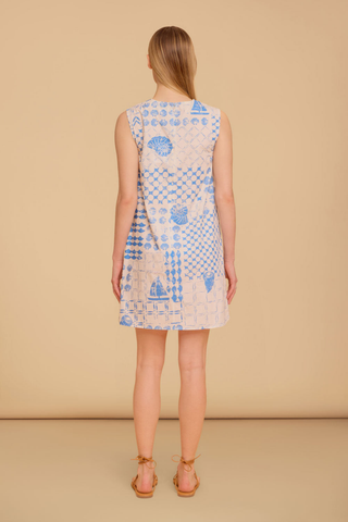 Model wearing the Olivia by Livro Wynn Dress in Sea Atlas featuring a sleeveless shift silhouette, blue coastal-inspired patchwork print with shell and sailboat motifs, mini length, and lace-up flat sandals