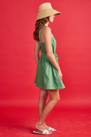 Woman wearing a green dress and beige hat on a red background