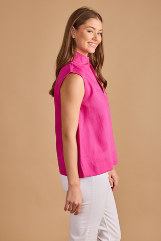 Model wearing the Double A Sandy Top in Fuchsia featuring a sleeveless silhouette, stand collar, split neckline, and relaxed fit paired with white denim