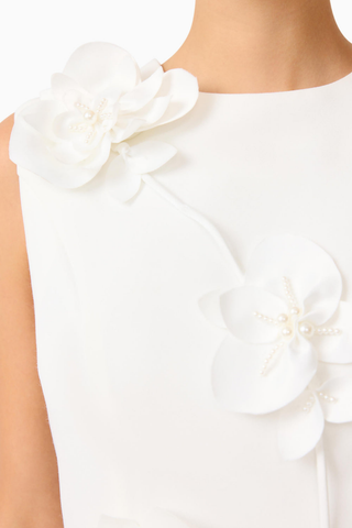 Model wearing the Elliatt Reina Mini Dress in White featuring a sleeveless silhouette, intricate 3D floral appliqué, and a structured A-line mini dress.