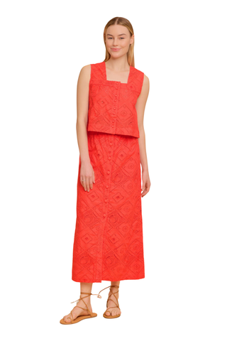 Model wearing the Olivia by Livro Fawn Skirt in Netta featuring vibrant coral eyelet embroidery, a midi-length straight silhouette, covered button front detailing, and matching coordinating top styled with lace-up sandals by the water