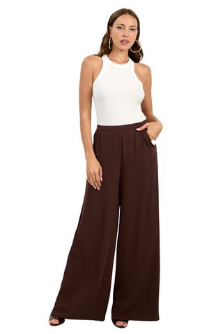 Woman wearing a white sleeveless top and brown wide-leg pants on a white background