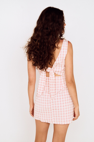 Model wearing the MINKPINK Sabina Tie Back Mini Dress in Pink Gingham featuring a fitted bodice, tie-back detail, and classic pink gingham print.