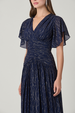 Shoshanna Lilly Dress in Indigo Silver and Gold featuring shimmering lurex chiffon, a V-neckline, flutter sleeves, ruched waist, and flowing full-length skirt.