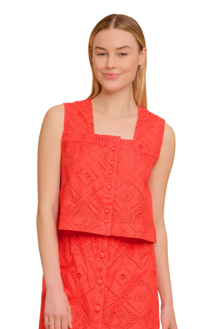 Model wearing the Olivia by Livro Nellie Top in Netta featuring vibrant coral eyelet embroidery, a sleeveless cropped silhouette, square neckline, covered button front detailing, and coordinating matching skirt styled with lace-up flat sandals