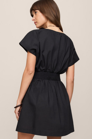 Model wearing the Z Supply Sanna Mini Dress in Black featuring a V-neckline, smocked waist, and short sleeves.
