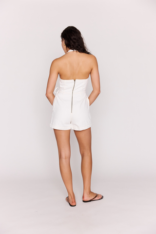 White denim sleeveless romper with wrap front and tie waist detail