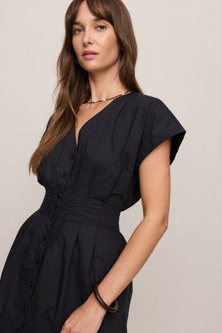 Model wearing the Z Supply Sanna Mini Dress in Black featuring a V-neckline, smocked waist, and short sleeves.
