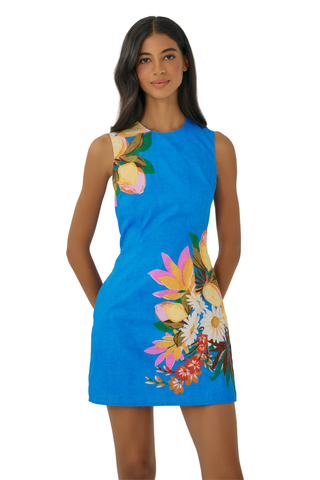 Model wearing the Hutch Janesta Dress in Zesty Lemon Tropical featuring a bright blue fabric, tropical floral placement print, sleeveless silhouette, and tailored mini dress design paired with neutral heels