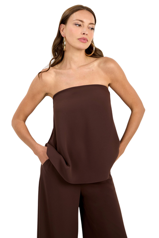 Woman wearing a strapless brown jumpsuit on a white background
