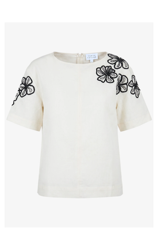 White blouse with black floral embroidery on sleeves against a white background