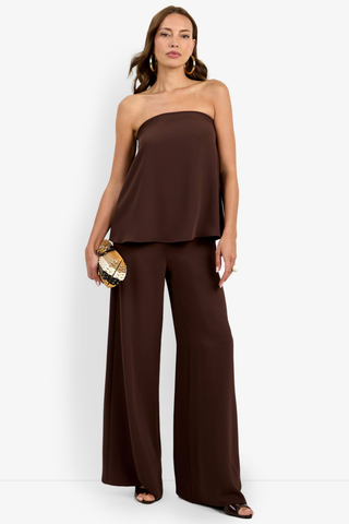 Woman wearing a brown strapless top and wide-leg pants on a white background