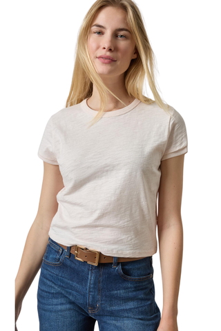 A woman wearing a light beige short-sleeve crewneck t-shirt and blue jeans with a brown belt, photographed against a plain white background.