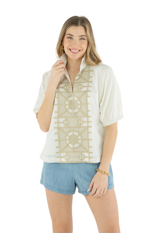 Woman wearing a white blouse with a geometric pattern and blue shorts on a white background