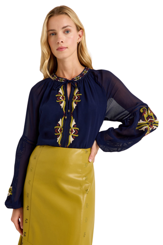 Marie Oliver Royce Blouse in Sundown featuring deep navy fabric, colorful embroidery, a tie neckline, and billowy sleeves.