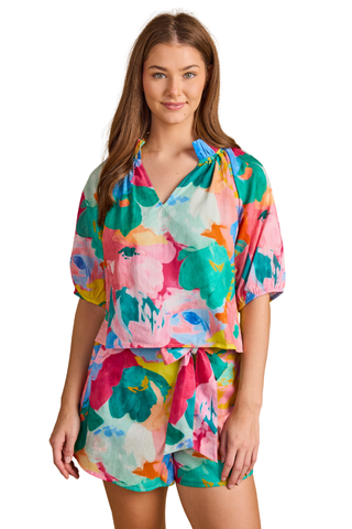 Model wearing the Double A Trish Top in Bougainville featuring a colorful floral print, puff sleeves, gathered ruffle collar, and relaxed silhouette paired with matching shorts