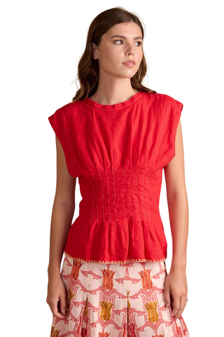 Model wearing Thomas & Lourdes Nala Top in Turkish Delight featuring pintuck waist detailing, cap sleeves, and a structured peplum silhouette