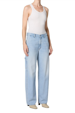 Model wearing the AGOLDE Lyndon Jean in Memory featuring a relaxed straight leg silhouette, oversized utility pockets, and a soft light wash denim paired with a fitted neutral tank top