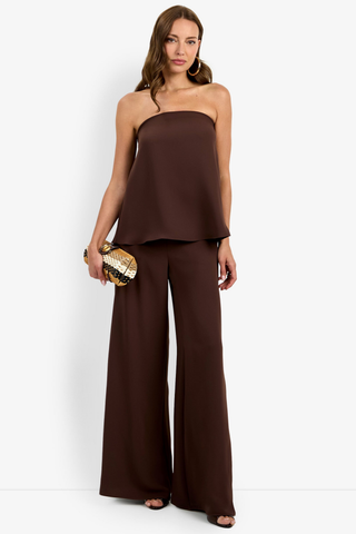 Woman wearing a brown strapless top and wide-leg pants against a white background