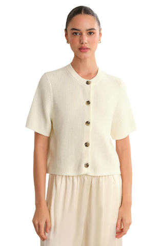 Model wearing the 525 Ginevra Cardigan in Chalk featuring a cream shaker stitch knit, short sleeves, crew neckline, and button-front detail