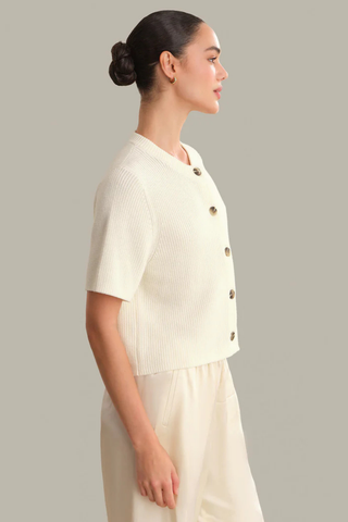 Model wearing the 525 Ginevra Cardigan in Chalk featuring a cream shaker stitch knit, short sleeves, crew neckline, and button-front detail