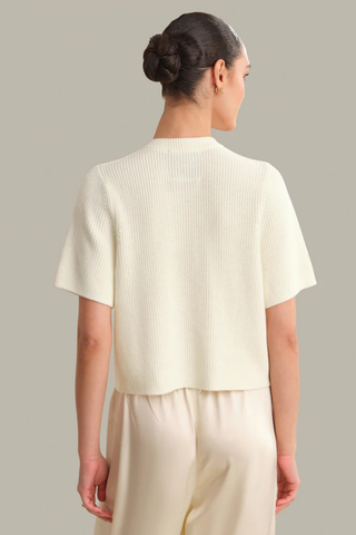 Model wearing the 525 Ginevra Cardigan in Chalk featuring a cream shaker stitch knit, short sleeves, crew neckline, and button-front detail