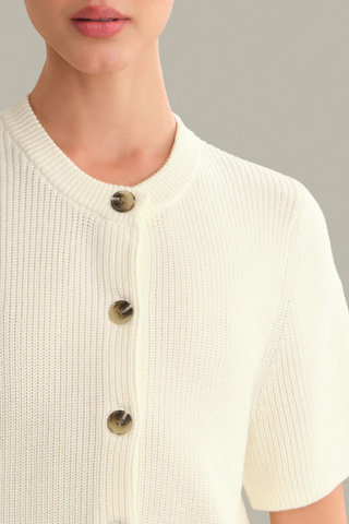 Model wearing the 525 Ginevra Cardigan in Chalk featuring a cream shaker stitch knit, short sleeves, crew neckline, and button-front detail