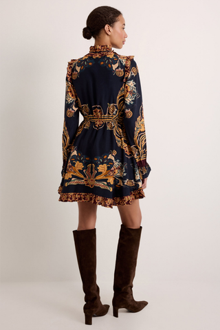 Thalia Dress in Lasso featuring a navy Western-inspired print, long sleeves, ruffle detailing, and a handkerchief mini hem.