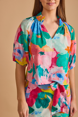 Model wearing the Double A Trish Top in Bougainville featuring a colorful floral print, puff sleeves, gathered ruffle collar, and relaxed silhouette paired with matching shorts