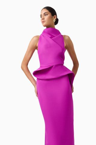 Elliatt Lioris Gown in Orchid featuring a rich purple hue, high neckline, asymmetric draped peplum, and floor-length silhouette.