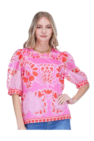 Model wearing the Jade Puff Sleeve Top in Pink Petal Lace featuring a vibrant pink and coral lace-inspired print, puff sleeves, relaxed silhouette, and statement border detailing paired with denim jeans