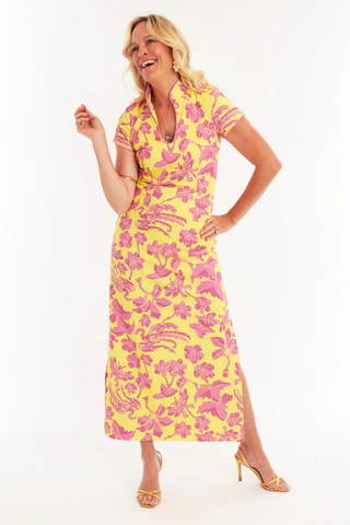 C.K. Bradley Tarpon maxi dress in Lingren Sunset print featuring pink floral motifs on a yellow background, short sleeves, mandarin collar, and side slits
