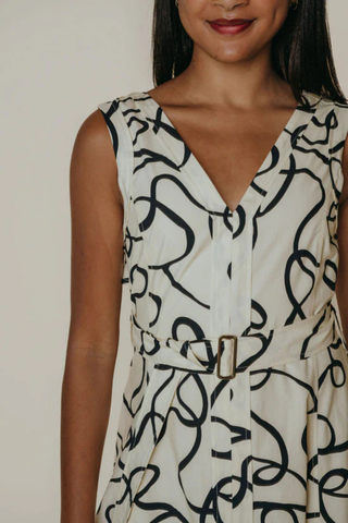 Woman wearing a sleeveless dress with black abstract pattern on a plain background