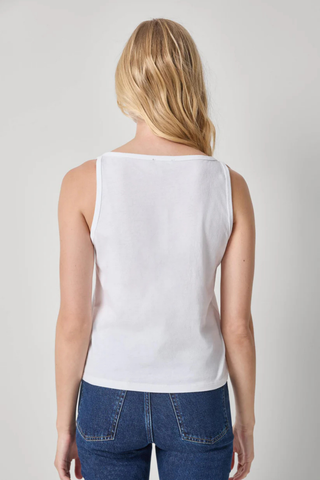Person wearing a white sleeveless top and blue jeans on a plain background