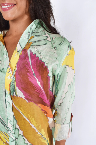 Woman wearing a yellow and pink botanical print midi dress with button front, collar, and rolled sleeves by Emily Phillips on a white background.
