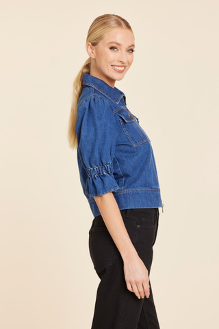Dolce Cabo Puff Sleeve Shacket in Denim featuring medium wash denim, elbow-length puff sleeves, a pointed collar, zip front, and chest flap pockets.