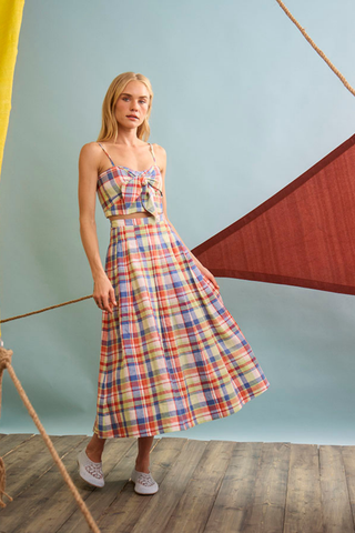 Woman wearing a plaid dress standing against a light blue wall.