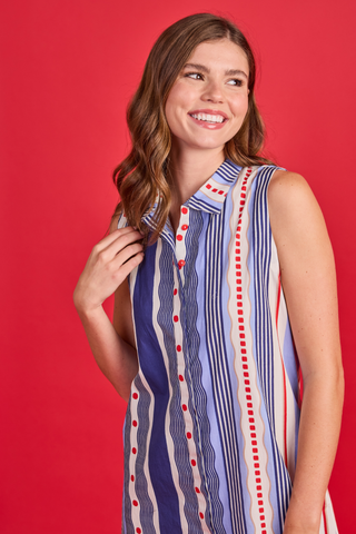 Woman wearing a sleeveless, patterned dress against a red background