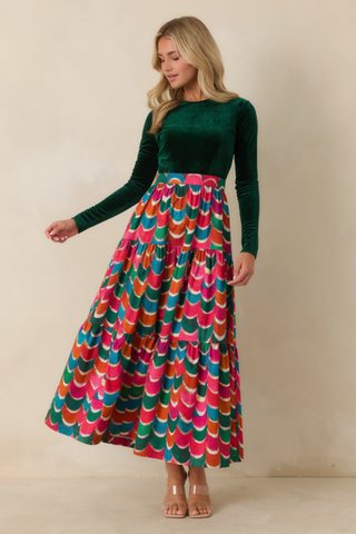 Prosperina Fontaine Maxi Dress in Party Planner featuring a deep emerald green long-sleeve bodice and a full flowing maxi skirt in a vibrant multicolor geometric print.