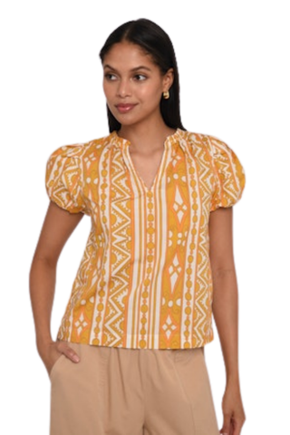 Model wearing the Love the Label Lia Top in Bowen Deco Print featuring puff sleeves and a golden geometric print.