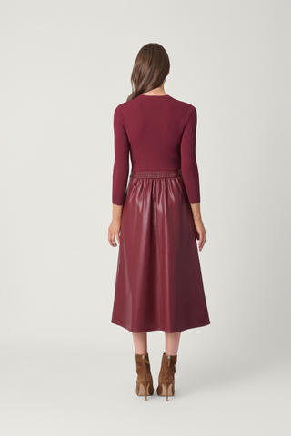 Shoshanna Paige Dress in Burgundy featuring a ribbed knit bodice, three-quarter sleeves, faux leather midi skirt, and buckle waist detail.