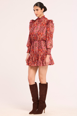 Misa Gianna Dress in Boheme Mix featuring a vibrant red and pink bohemian print, high smocked neckline, long blouson sleeves, and tiered ruffle mini skirt.