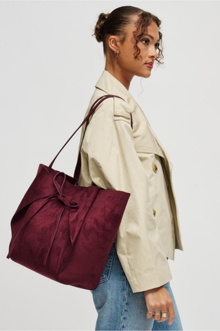 Urban Expressions Soren Tote in Burgundy vegan suede with long shoulder straps, bow-front detail, and matching zip pouch.