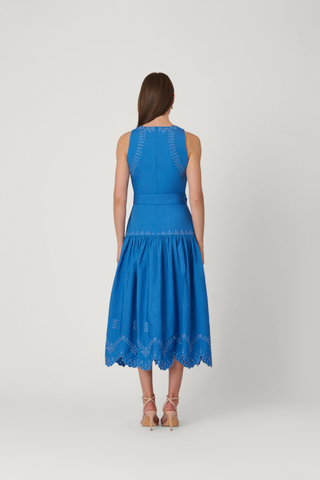 Model wearing the Shoshanna Lennon Dress in Marina, a sleeveless blue midi dress with a fitted bodice, textured detailing, and flowing skirt.