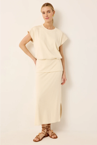 Woman wearing a cream-colored outfit against a white background